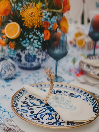 A beautiful tablescape featuring blue and white patterned plates, complemented by vibrant orange florals. This unexpected color combination creates a fresh and stylish look.