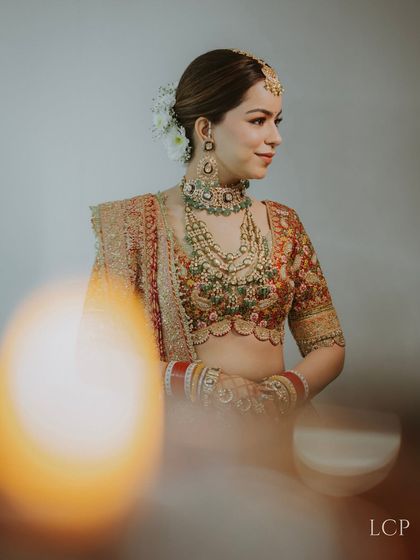 An artistic bridal portrait taken through a foreground object, creating a dreamy, soft-focus effect.