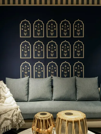A custom-built seating area with a light blue upholstered bench set against a deep navy wall. The wall is adorned with traditional Indian block print motifs, and the space is accessorized with tablas, reflecting a blend of modern and cultural design.