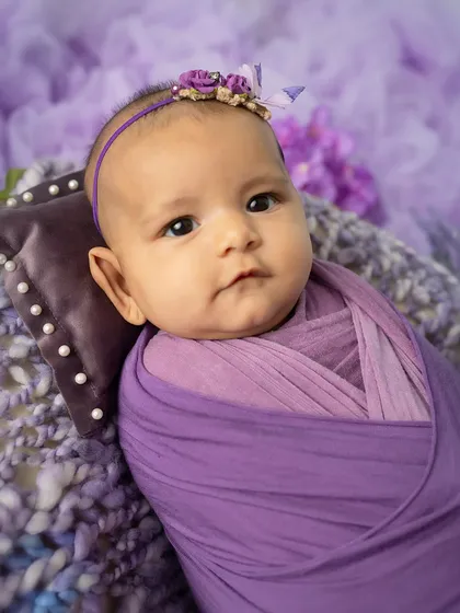 A regal portrait. This close-up shot in a purple wrap highlights the baby's beautiful eyes and serene expression.