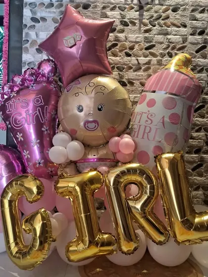 Celebrating a new arrival? We create stunning balloon arrangements like this 'It's a Girl' bouquet to make your baby shower unforgettable. This setup features large foil letters, a baby-shaped balloon, and a mix of pink and gold accents.