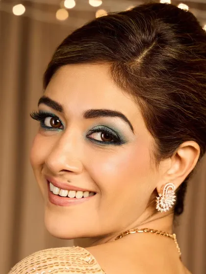 A touch of vintage glamour. This look features a classic French roll hairstyle and a teal-toned smokey eye, perfect for a themed cocktail party or a sophisticated reception.