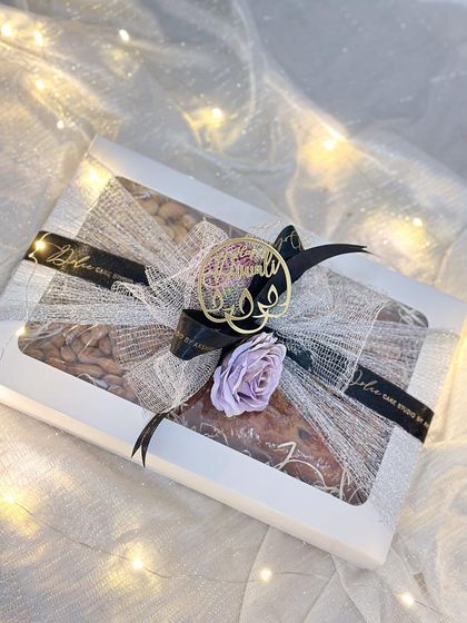 A beautifully lit shot of my Diwali box hamper, showing the elegant packaging with silver mesh, a black ribbon, and a lavender flower. It’s all in the details!