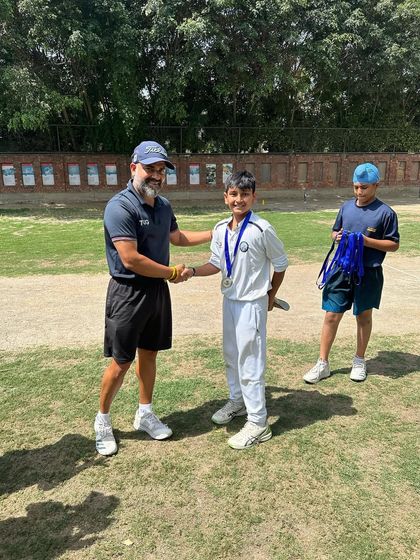A coach congratulates a young player with a medal after a successful tournament. We believe in acknowledging the effort of every single player.