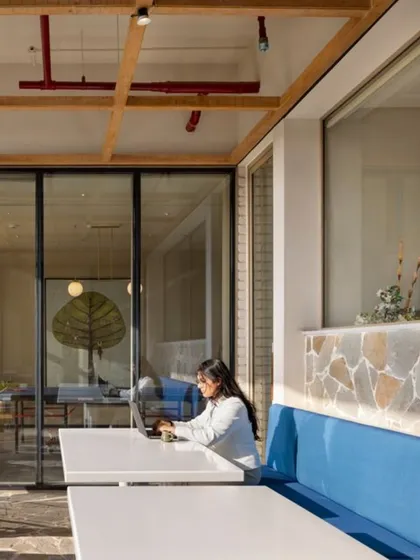 Blurring the lines between inside and out is a key part of our philosophy. This semi-outdoor seating area provides a tranquil spot for work or relaxation, combining natural materials like stone and wood with comfortable furnishings to create a peaceful escape within the community hub.