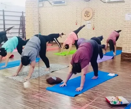 This is the three-legged downward dog, an excellent pose for building upper body strength and opening the hips. You can see the different levels of flexibility in the group.