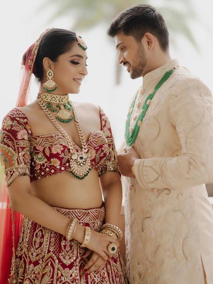 A sweet moment between the bride and groom. Her bold eye makeup and radiant skin create a stunning contrast with her partner's classic ivory sherwani.