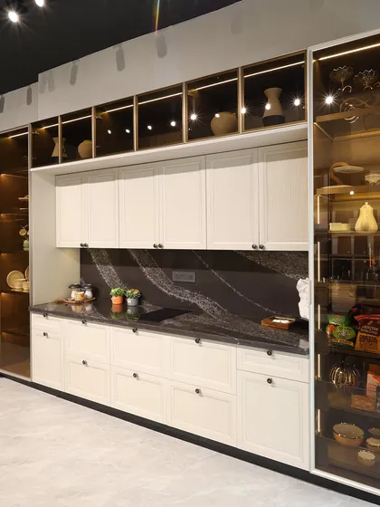 An angled view of the same kitchen, showing the deep countertop and extensive storage. The dark marble backsplash provides a beautiful contrast to the off-white cabinetry.