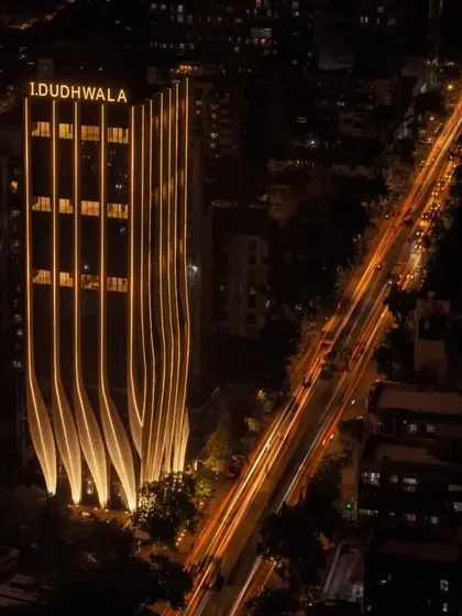 An aerial view showing the full length of the illuminated building against the city grid, emphasizing its linear form and urban presence.