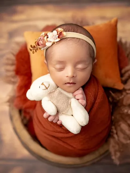 A pop of autumn color. This newborn, wrapped in rust-colored fabric and holding a tiny teddy, looks so cozy and warm.