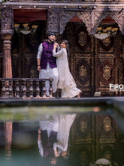 A beautiful reflection shot captures the elegance of this couple against our intricately carved wooden doors, a set that adds a touch of antique grandeur.