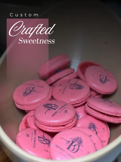 A bowl of our custom-crafted pink macarons, branded with a client's logo. This is a perfect example of our bespoke dessert offerings.
