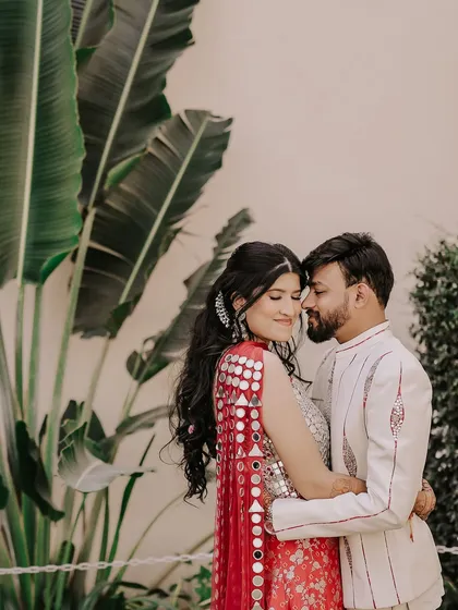 A serene moment of togetherness. With foreheads touching, this portrait is all about the quiet connection and peaceful love the couple shares, framed by lush tropical leaves.