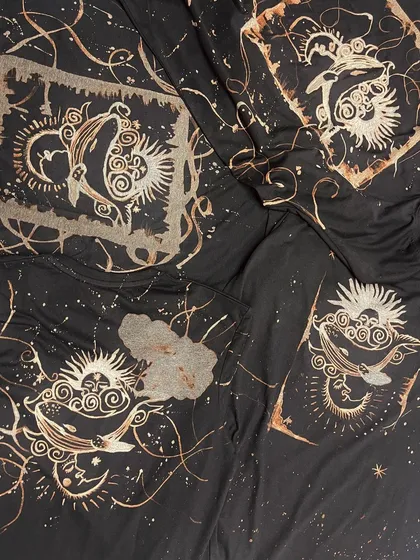 A collection of different t-shirts from a bleach art workshop, featuring celestial and whale motifs.
