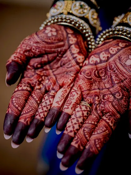 A macro shot of the "PulseToPromises" hashtag woven into the bride's mehendi, a clever nod to her medical profession.