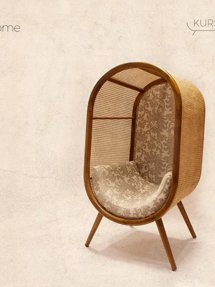 For those who want a truly unique statement piece, I created the 'Dome' chair. Its cocoon-like shape, formed from bent teak and woven rattan, offers a private, cozy nook for reading and relaxing. It’s a conversation starter that blends artistry with comfort.