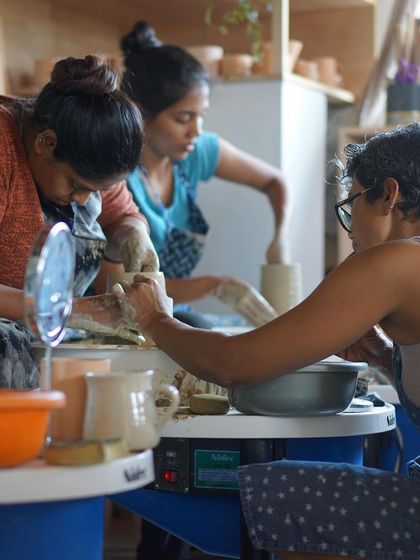A view of three students working in unison at their wheels, a beautiful image of shared focus and creative energy.