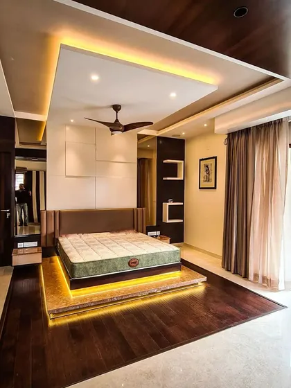 This master bedroom is a sanctuary of modern comfort, centered around a custom floating platform bed with warm LED under-lighting. I used a combination of dark wood flooring, a multi-layered false ceiling with cove lighting, and a minimalist white panelled accent wall to create a sophisticated and restful atmosphere.