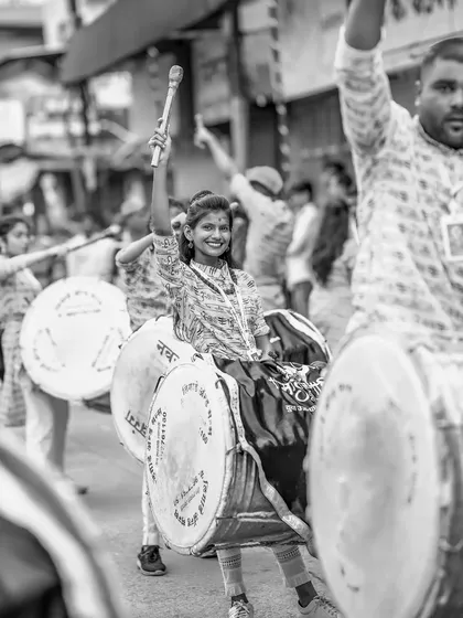 A classic black and white shot of the proud female dhol player, capturing a moment of celebration and strength.