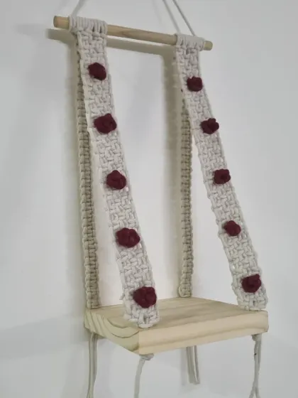 This macrame wall shelf combines a natural wood base with knotted hangers, creating a functional and beautiful piece. The small, deep red rose details add a unique, romantic touch.