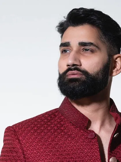 A profile view showcasing the sharp cut and structured shoulder of our crimson bandhgala. Every detail is considered to create a garment that is both comfortable and visually striking.