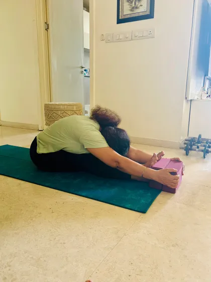 As flexibility improves, you can deepen the Paschimottanasana stretch. This photo shows the progress, moving from using blocks to reaching the feet, always maintaining a long spine.