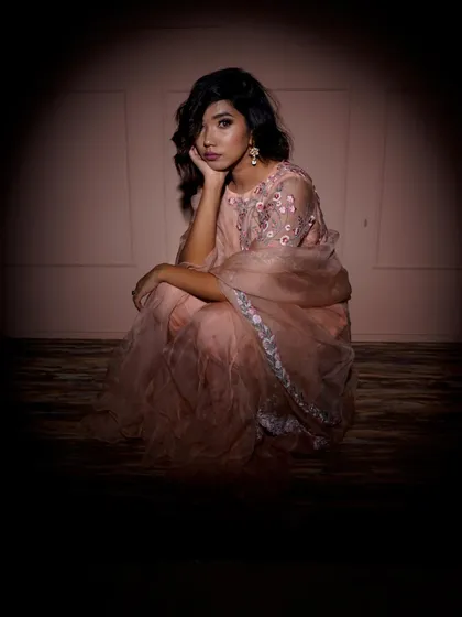 A contemplative seated pose, framed within a circle of light. This artistic choice creates a sense of intimacy and draws the viewer's eye directly to the model and her elegant outfit.