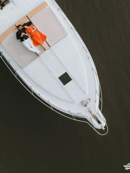 An aerial drone shot of a couple relaxing on a private yacht in Goa. This highlights my experience with destination pre-wedding shoots and creating unique, aspirational images.