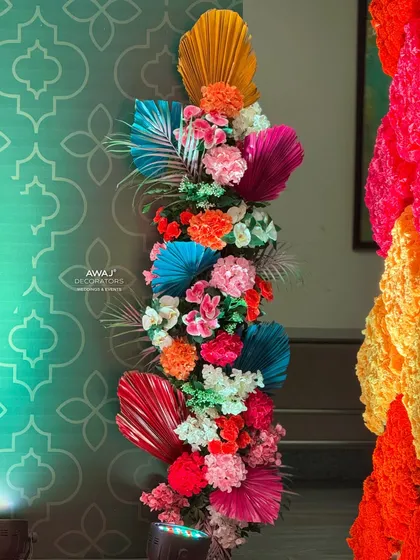 A stunning floral arrangement for a Mehendi, featuring a rainbow of colors and exotic palm leaves.