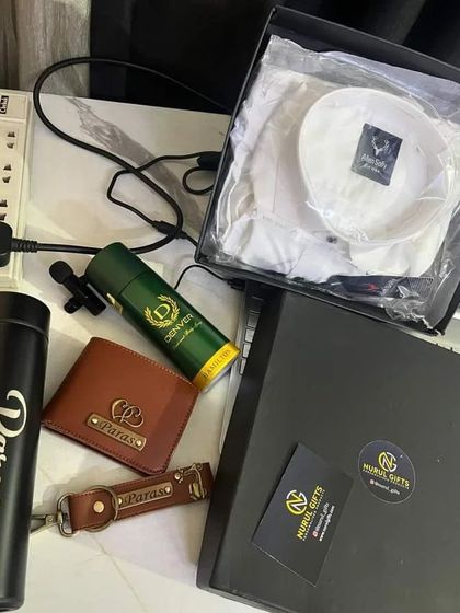 A customer's photo of their received hamper, laid out with the premium packaging. It includes a shirt, personalized wallet, keychain, and flask.