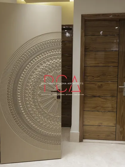 The main entrance door of The Cursive Abode residence, a testament to detailed craftsmanship. The door features an intricate, CNC-milled mandala pattern, serving as a bespoke art piece that provides a grand and welcoming entrance to the home.