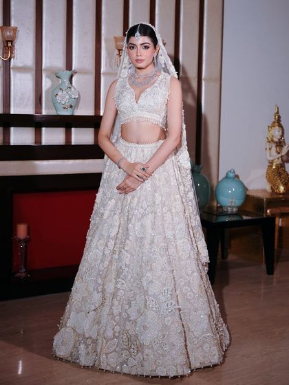 The full look of the bride in her intricate white lehenga. The makeup is kept clean and radiant, balancing the detailed couture and allowing her natural beauty to be the focus.