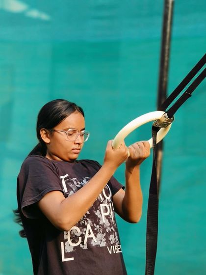 Getting strong on the gymnastic rings. This young woman is focused on building her upper body strength, one rep at a time.
