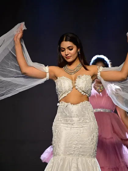 The model showcasing the ethereal sleeves of the gown. The makeup look is cohesive with the angelic yet strong vibe of the design.