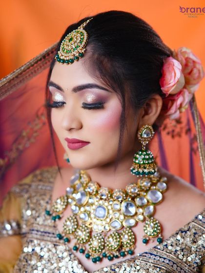 The soft, closed-eye pose is perfect for showing off the detailed eyeshadow work and the large, statement Kundan jewelry.