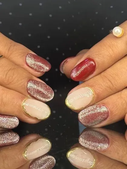 A chic and stylish manicure with red, nude, and glitter nails, featuring gold-outlined accents.