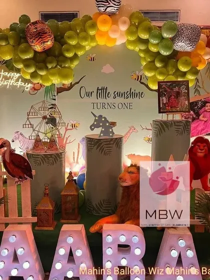 This shot captures the whimsical details and textures of the jungle party setup, from the stuffed lion to the wooden fence and custom name sign.
