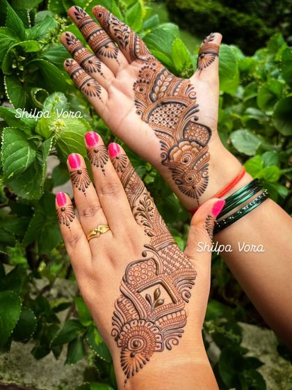 Two different but complementary designs on each hand, one with a square motif and the other with a flowing pattern.