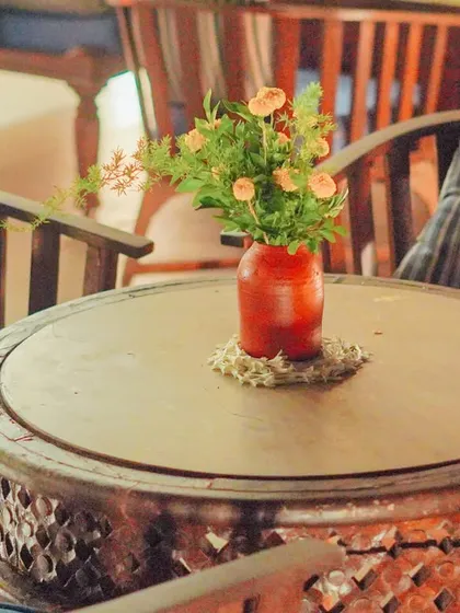 Even the simplest elements can elevate a space. A small, rustic vase with a few fresh flowers on a carved wooden table helps tie a seating area into the main event decor, ensuring a cohesive look throughout the home.