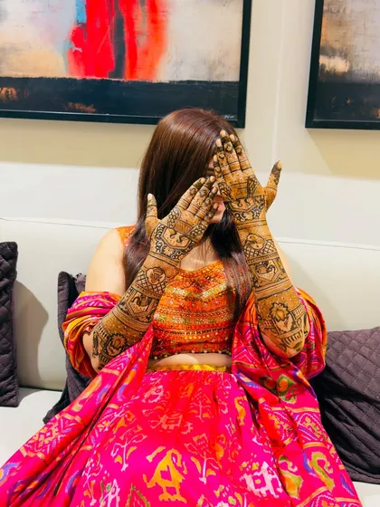 The classic "face-hiding" pose that beautifully showcases the intricate mehendi on both hands. The symmetry and detail are on full display.