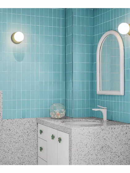 This girl's bathroom is a playful mix of color and texture. The walls are enveloped in blue and mint green mosaic tiles, paired with a terrazzo countertop. Quirky terrazzo wall lamps and a handmade arched mirror add to the fun, youthful character of the space.