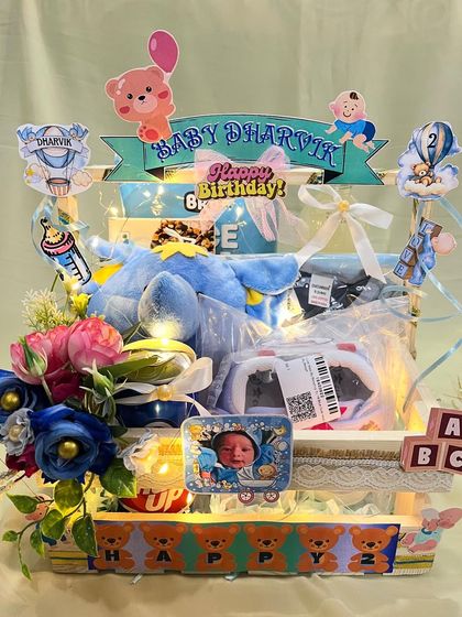 The full view of a stunning hamper celebrating a baby's 2 month milestone. It's lit with fairy lights and filled with toys, clothes, and personalized decorations to mark the special occasion.