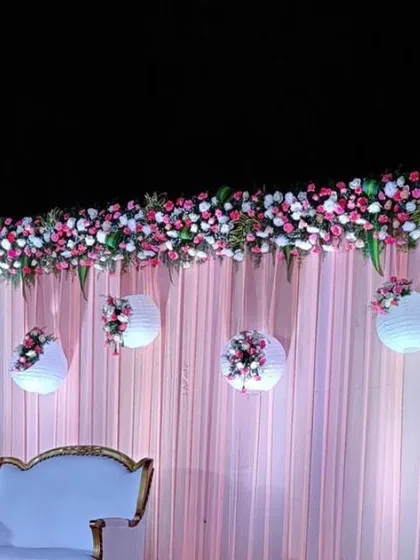 This engagement stage for a night ceremony features a soft pink draped backdrop. I added a thick border of pink and white flowers on top and hung decorated paper lanterns for a delicate and romantic touch.
