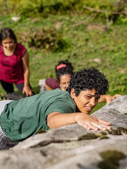 A climber tops out a boulder, looking back with a smile of accomplishment. These are the moments we live for.