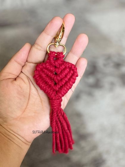 A single red heart keychain held in my hand. It's a simple, powerful symbol of love, all handmade.