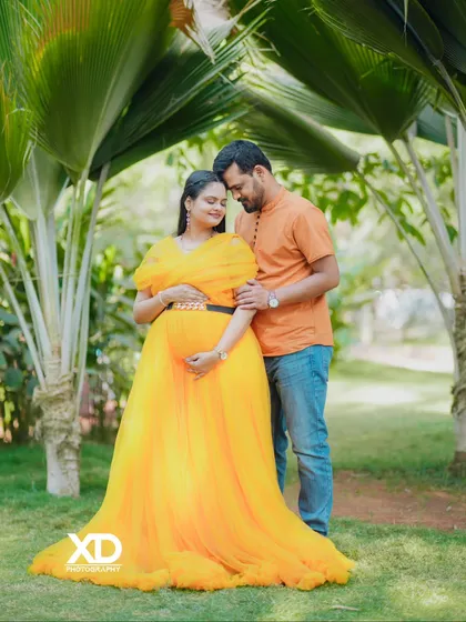 An intimate portrait of a couple in a garden, their hands gently placed on the baby bump.
