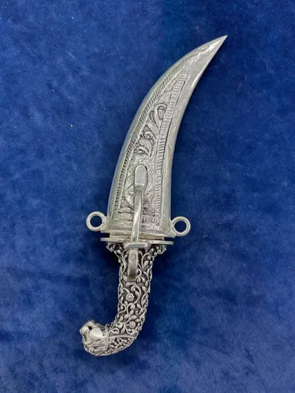 The antique silver dagger unsheathed, revealing its polished blade. The hilt is beautifully detailed with a lion head pommel and traditional engravings.