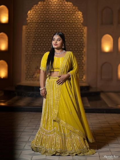 A full-length shot showing the beautiful yellow lehenga against a stunning backdrop. The makeup is bright and radiant for this evening look.