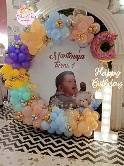 A sweet first birthday setup with a custom photo backdrop, pastel balloon ring, and a light-up number '1'.