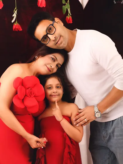 A sweet family huddle. This portrait captures the close bond between the parents and their daughter during their Valentine's themed photoshoot.
